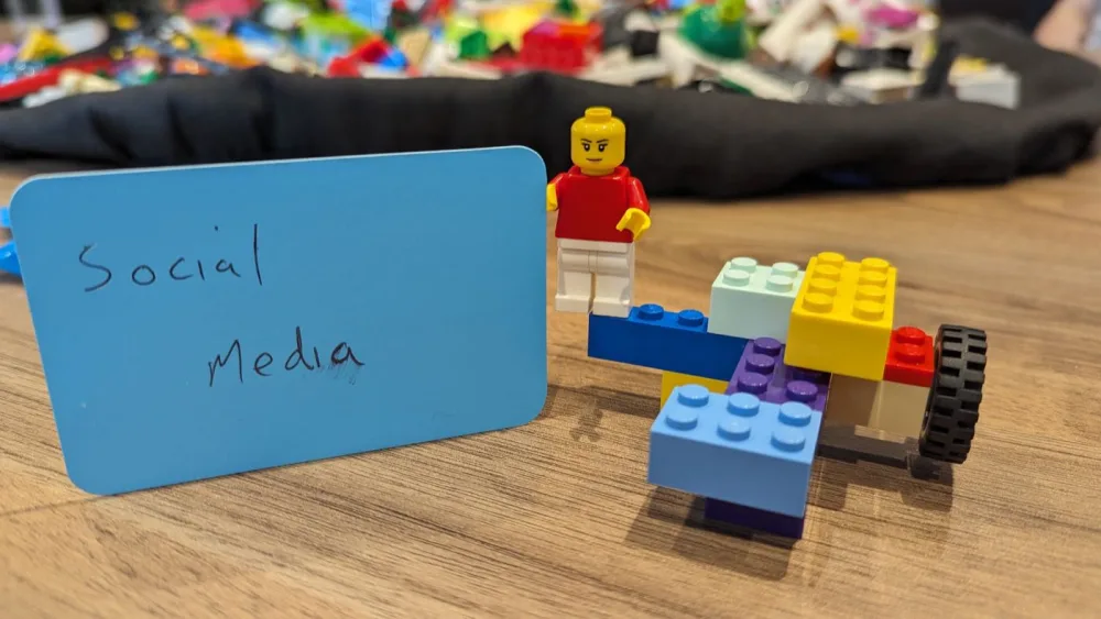 A LEGO Serious Play minifigure model with a handwritten sticky note reading Social media
